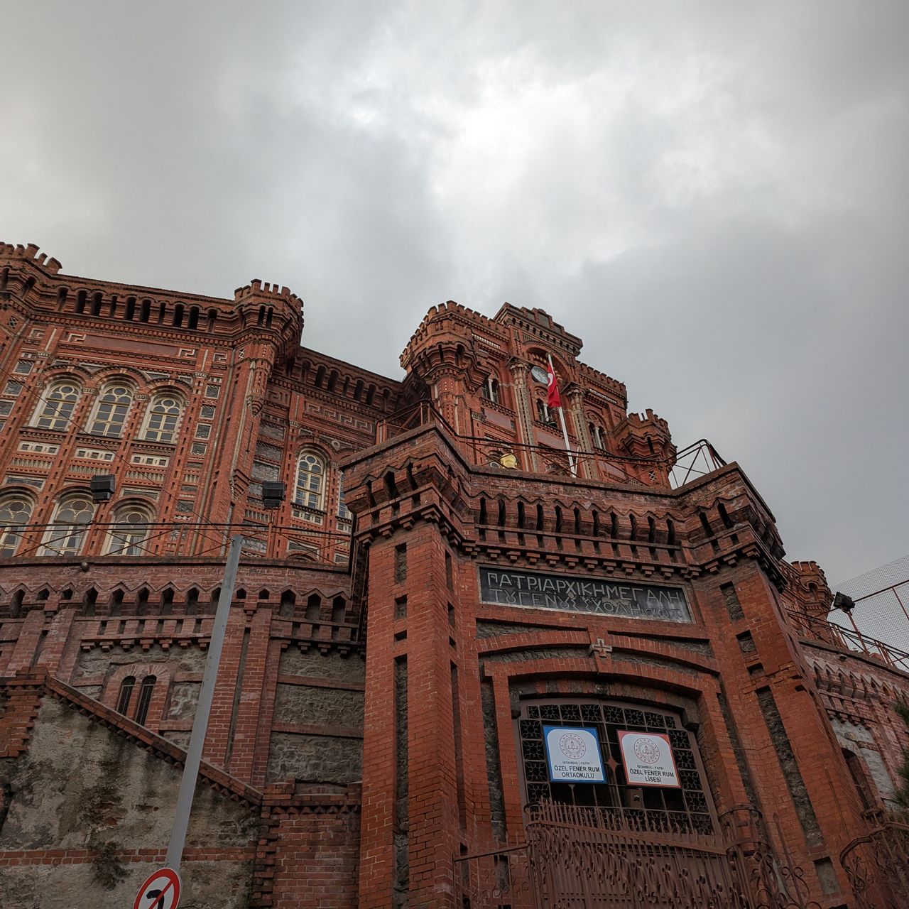Photo pris du bas d'un grand bâtiment couleur brique avec une inscription en grec devant, il s'agit du collège grec orthodoxe de Phanar, la plus ancienne école grecque orthodoxe d'Istanbul.